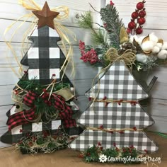 two wooden christmas trees decorated with plaid bows and pine cones are sitting next to each other