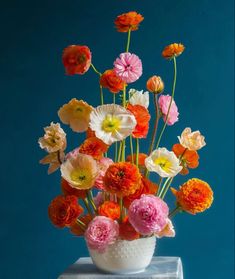 a white vase filled with lots of colorful flowers