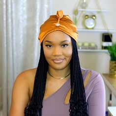 a woman with long braids wearing an orange headband and looking at the camera