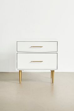 a white and gold dresser with two drawers on one side, against a white wall