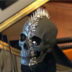 a skull with spikes on its head sitting in front of a piano