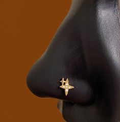 a close up of a nose with an earring on it's side and a gold star in the middle