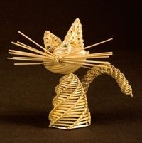 a cat made out of bamboo sticks sitting on top of a black surface with its eyes closed