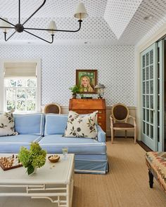 a living room with blue couches and white tables in front of a large window