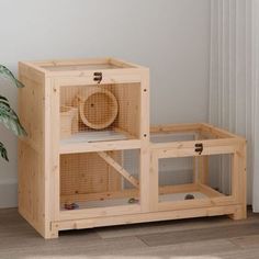 a small wooden cage sitting on top of a floor next to a potted plant