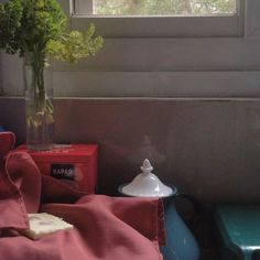 a vase filled with flowers sitting on top of a table next to a red blanket