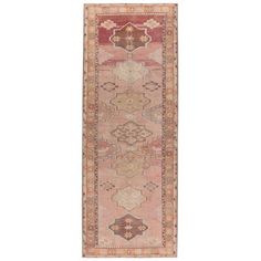 an antique persian runner rug in pink and orange tones, with geometric designs on the border