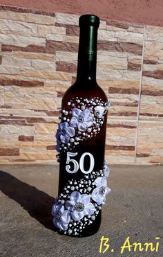 a wine bottle decorated with white flowers and the number 50 on it's side