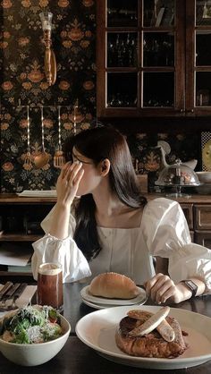 a woman sitting at a table with plates of food