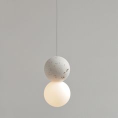 two white balls hanging from the ceiling with one light on it's side and another in the background