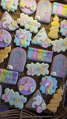 decorated cookies in the shape of unicorns and rainbows on a wicker basket