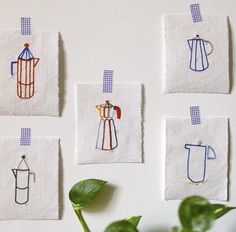 four tea towels with different colored coffee cups on them and a potted plant in the foreground