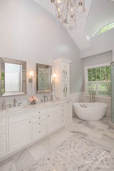 a large white bathroom with two sinks and a bathtub in it's center