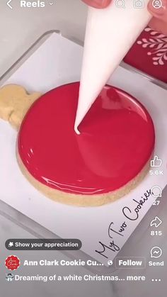 someone is decorating a cookie with red icing