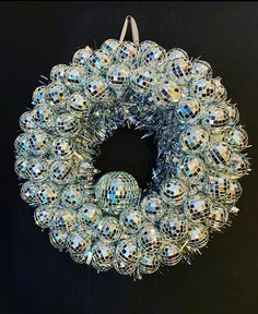 a christmas wreath with disco balls hanging from it's side on a black wall