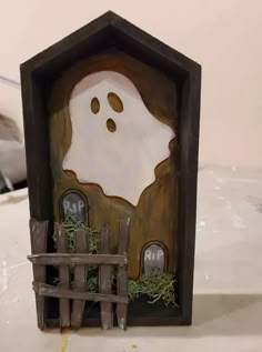 there is a small house made out of wood and fake grass in the shape of a ghost