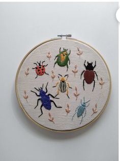 an embroidery project with bugs and ladybugs on it's side, in the shape of a circle