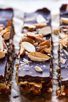 several pieces of chocolate and nuts on top of a piece of parchment paper with one slice cut in half