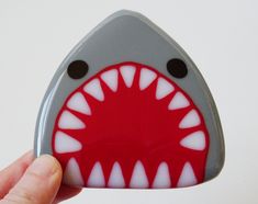 a hand holding up a shark shaped magnet