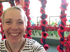 a woman is smiling in front of some red flowers