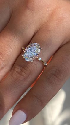 a woman's hand with a ring on her finger and an oval shaped diamond in the middle