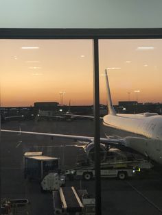 an airplane sitting on the tarmac at sunset as it is being loaded with luggage