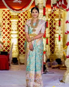 a woman in a blue and white sari standing next to a stage with flowers on it