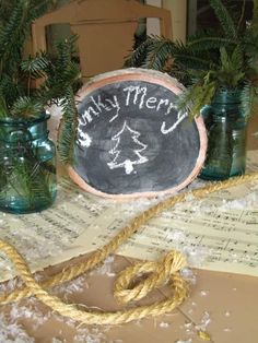 there is a chalkboard on the table with pine branches in mason jars next to it