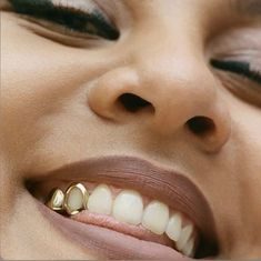 a close up of a woman's face with gold teeth and nose piercings