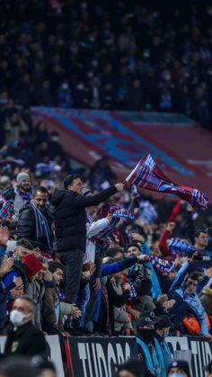 a man holding a red and blue flag in the middle of a stadium filled with people