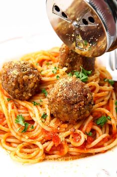 spaghetti with meatballs being sprinkled on top