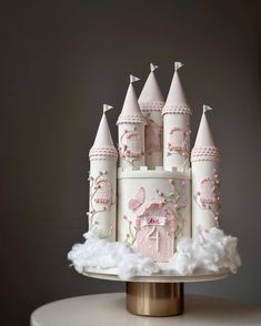 a white cake with pink castle decorations on it's side and clouds in the foreground