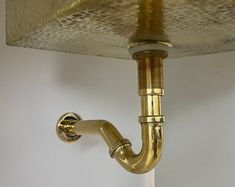 a gold faucet mounted to the side of a white wall