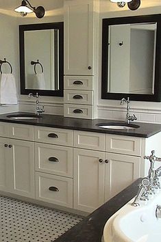 two sinks and mirrors in a bathroom with white cabinets, black counter tops and drawers