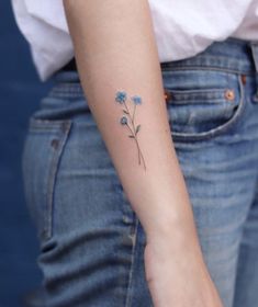 a small blue flower tattoo on the left arm