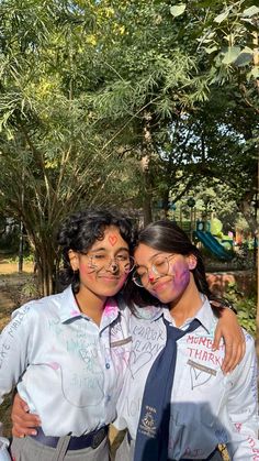 two girls with painted faces and ties posing for the camera in front of some trees