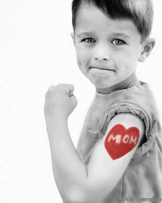 a young boy with a red heart on his arm and the word mom painted on it