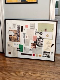 a white framed art piece with many different papers on it sitting in front of a door