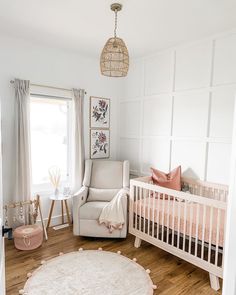 a baby's room with a white crib and pink accents