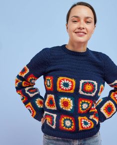 a woman wearing a blue sweater with colorful crocheted squares on the front and sides