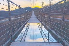 a bridge that is very high in the sky with water reflecting it's reflection