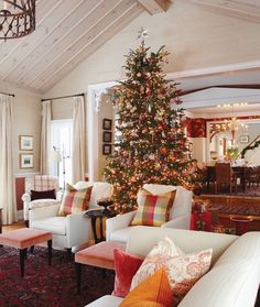 a living room filled with white furniture and a christmas tree in the middle of it