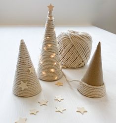 twine wrapped christmas trees with lights on them and stars scattered around the top, sitting on a white surface