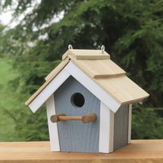 a bird house on a wooden table with trees in the background