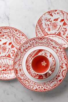 four red and white plates on a marble surface with a tea cup in the middle