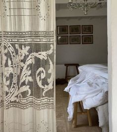 a bedroom with a bed, chandelier and curtain in the doorway to another room