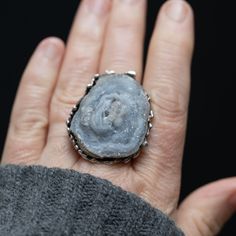 Introducing our handmade, bohemian-inspired Druzy Stone Ring! This stunning piece features a large, 39mm x 27mm silver blue grey druzy stone with lots of sparkle and an ultra-cool organic design. The organic stone looks like it was poured into the pebble bezel setting, giving it a truly unique and one-of-a-kind look. The sterling silver thick band is also organically detailed, adding to the overall bohemian feel of this ring. Crafted with care, this ring is handmade with attention to detail and Artisan Silver Freeform Jewelry, Bohemian Silver Jewelry With Large Stone, Unique Silver Gemstone Geodes, Unique Silver Geode Gemstones, Unique Silver Geode With Gemstone Details, Unique Silver Geodes As Gift, Unique Silver Geodes For Gifts, Handmade Silver Geodes For Jewelry Making, Bohemian Gray Jewelry With Natural Stones