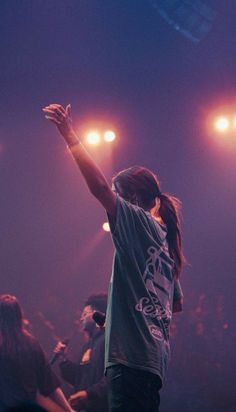 a man standing on top of a stage with his arms in the air and hands raised