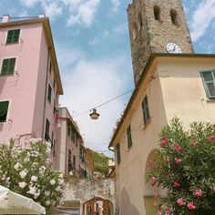 an alley way with pink buildings and a clock tower on the top of each building