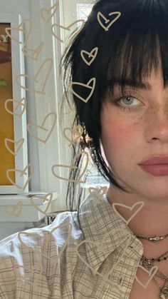 a woman with short black hair wearing a collared shirt and heart necklaces on her neck